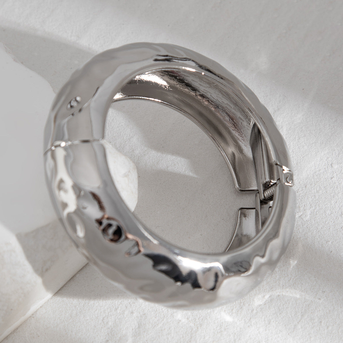 Bracelet à ressort, rond et lisse, au design sophistiqué et à l'aspect métallique irrégulier et tendance